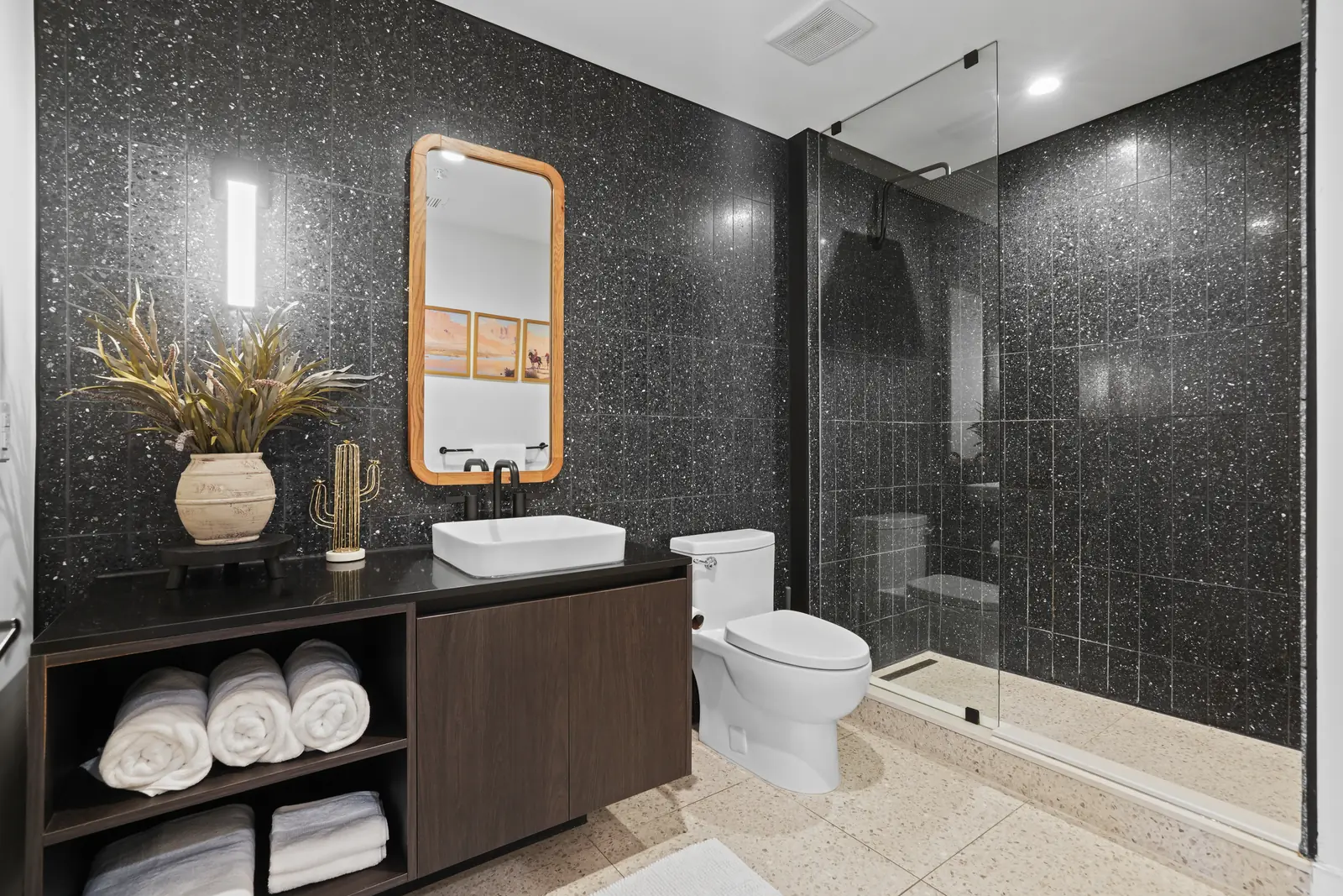 Bathroom with floating vanity, rolled towels and a glass-enclosed walk-in shower
