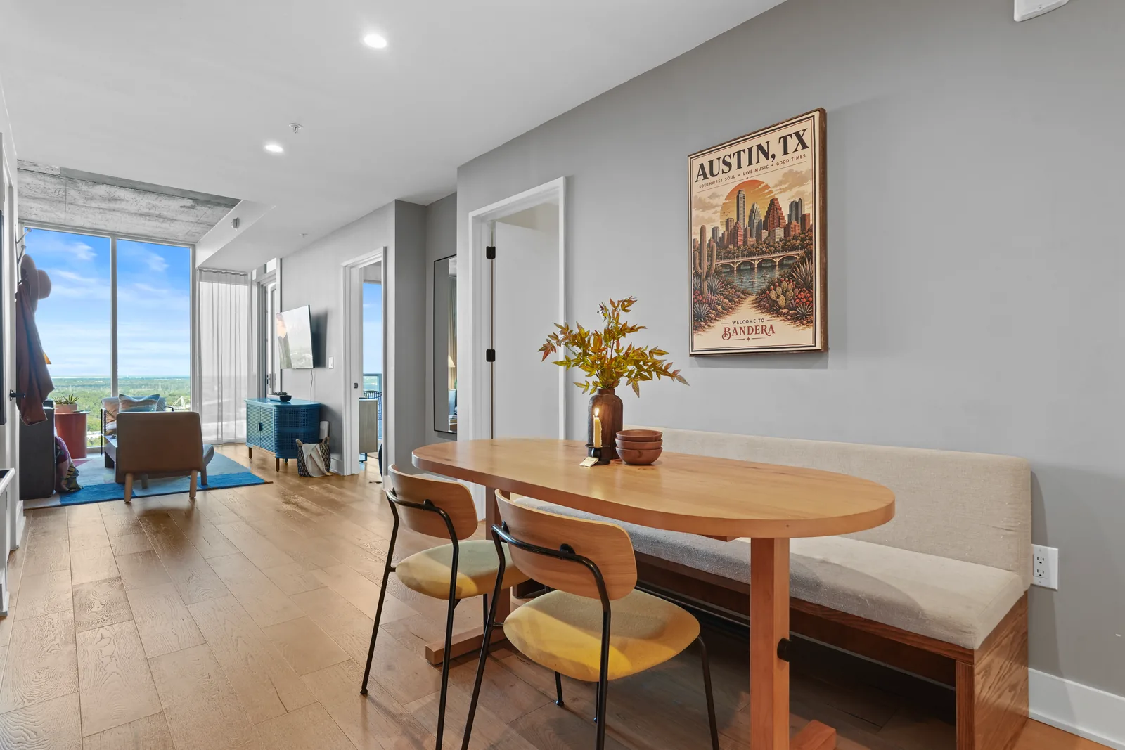 Dining table and Austin poster, with the living room and floor-to-ceiling windows in the distance