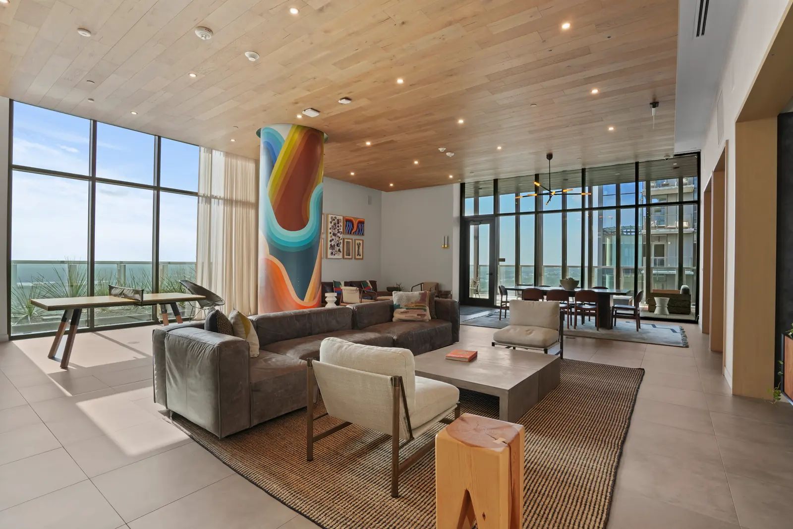 Shared lounge with a mural-painted column, leather sectional, table-tennis table and floor-to-ceiling windows