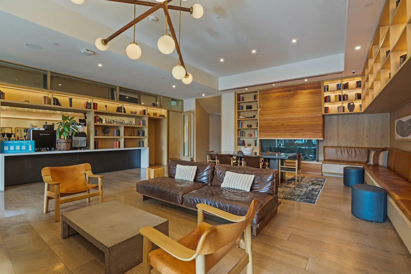 Shared lobby lounge with leather sofas, built-in bookshelves, a coffee bar and a see-through fireplace